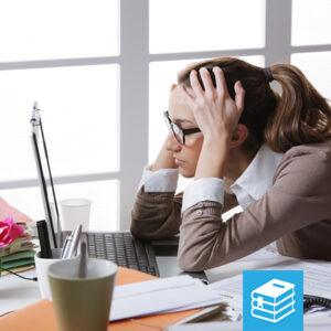 Student with head in hands at a desk with a laptop